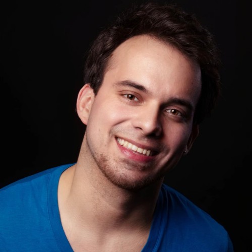 Headshot of Diego Mariscal smiling. He is a Mexican man with dark brown hair and light stubble facial hair. He is wearing a blue shirt.