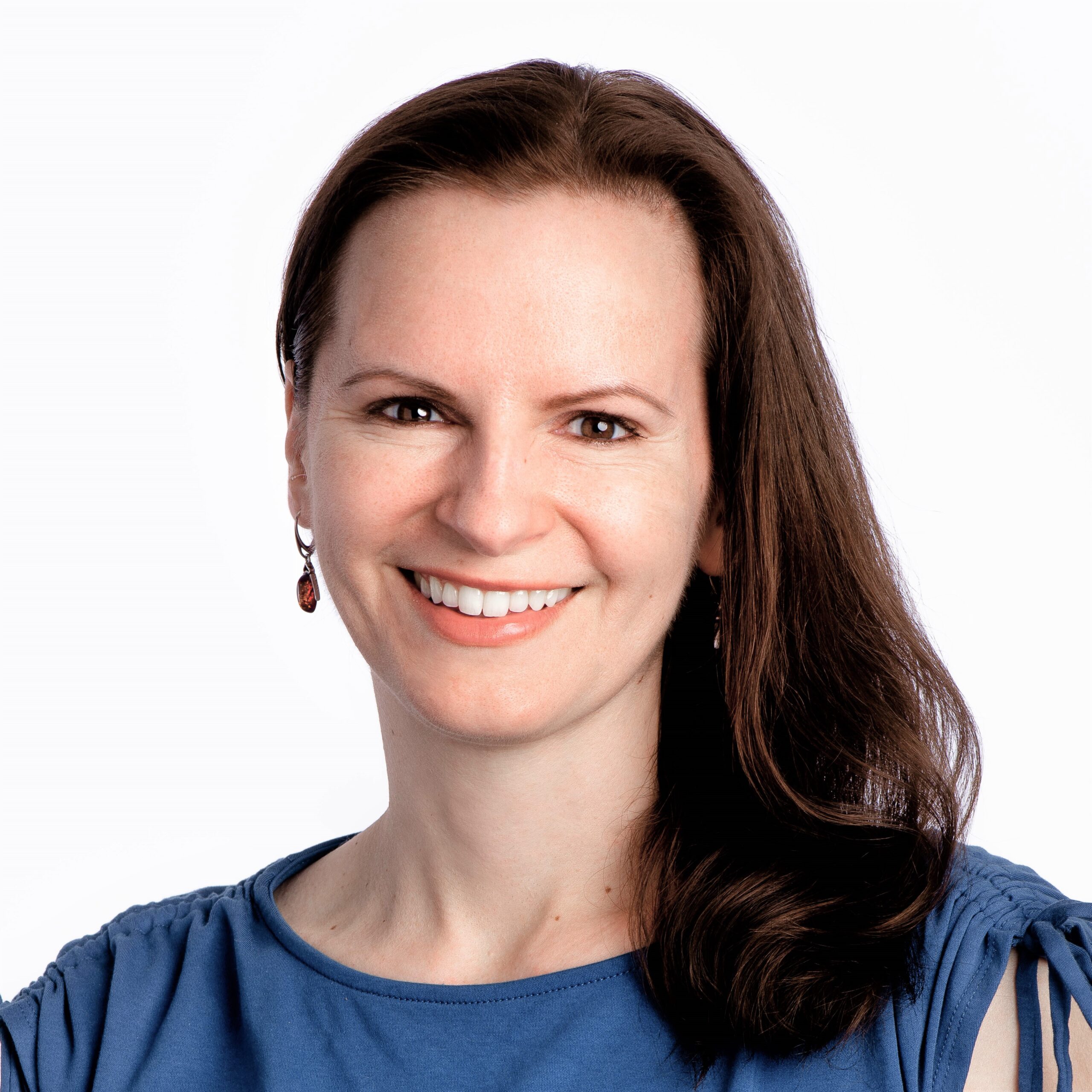 A smiling headshot of Kate Kalcevich, a white woman with shoulder-length brown hair pulled to one side. She is wearing red drop earrings and a blue shirt.