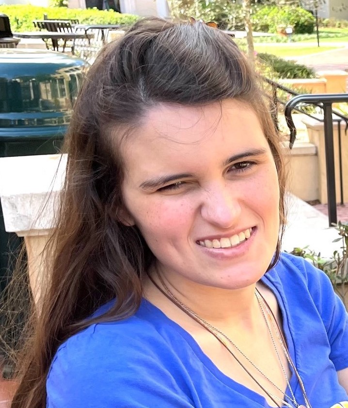 A headshot of Elizabeth Bonker, a white woman with long dark brown hair wearing a blue shirt smiling.