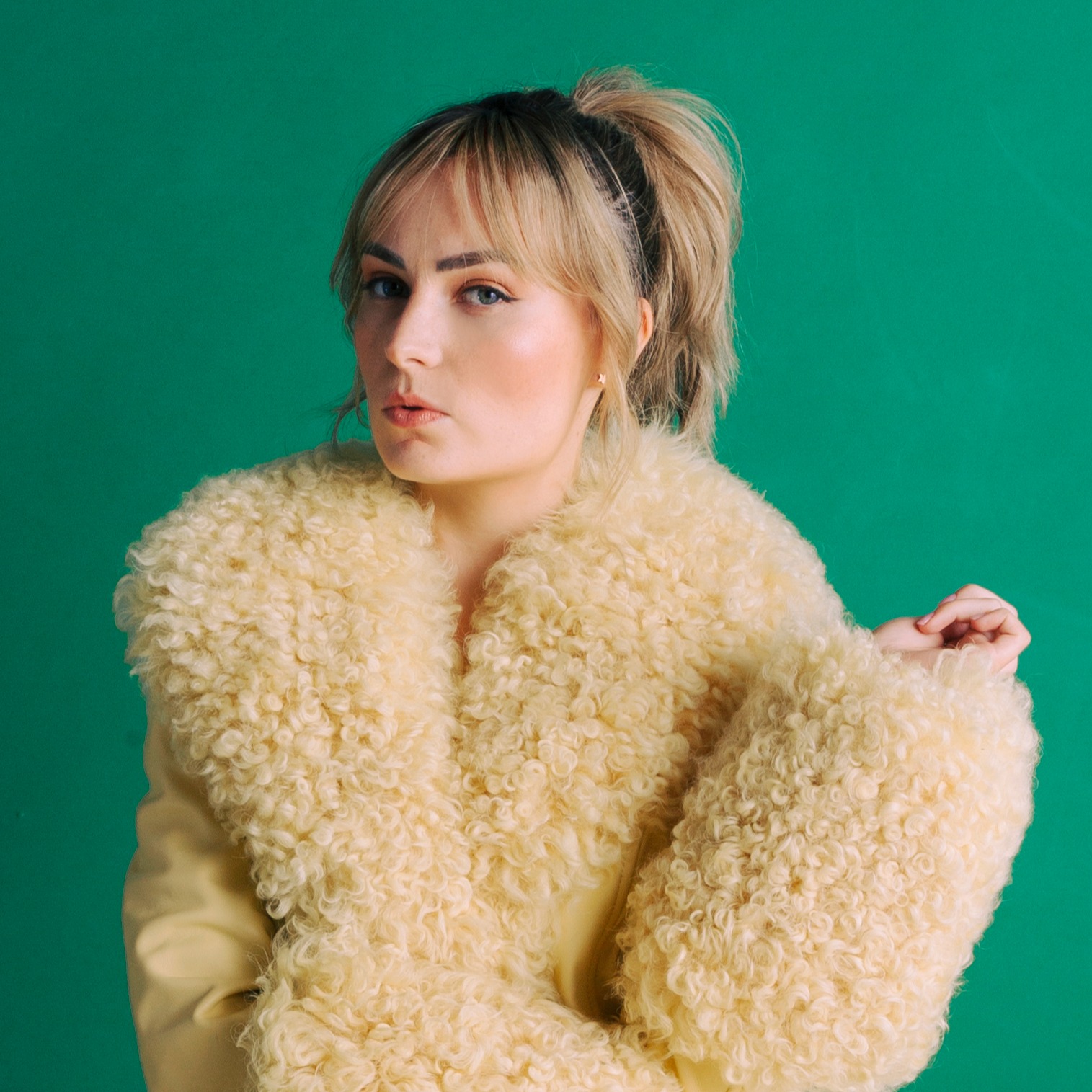 Headshot of Molly Burke, a white woman with blonde hair in a pony tail wearing a fur coat.