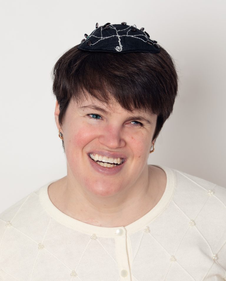 Lauren Tuchman, a white woman wearing a yarmulke and cream sweater.