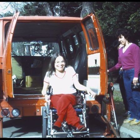 Judy in wheelchair outside van Judy unloading from a van